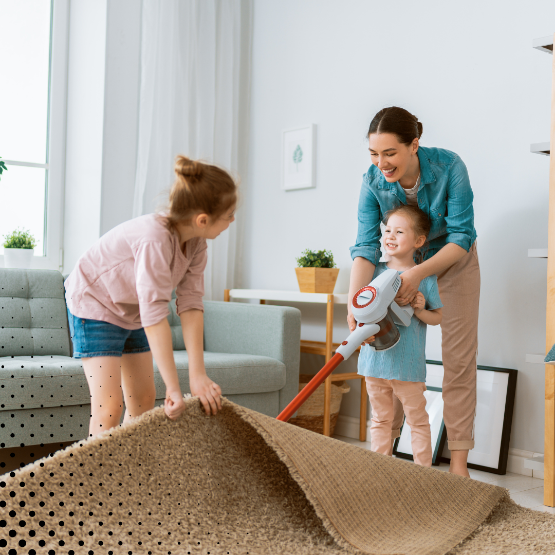 A mom and her children having fun as they clean the living room together 