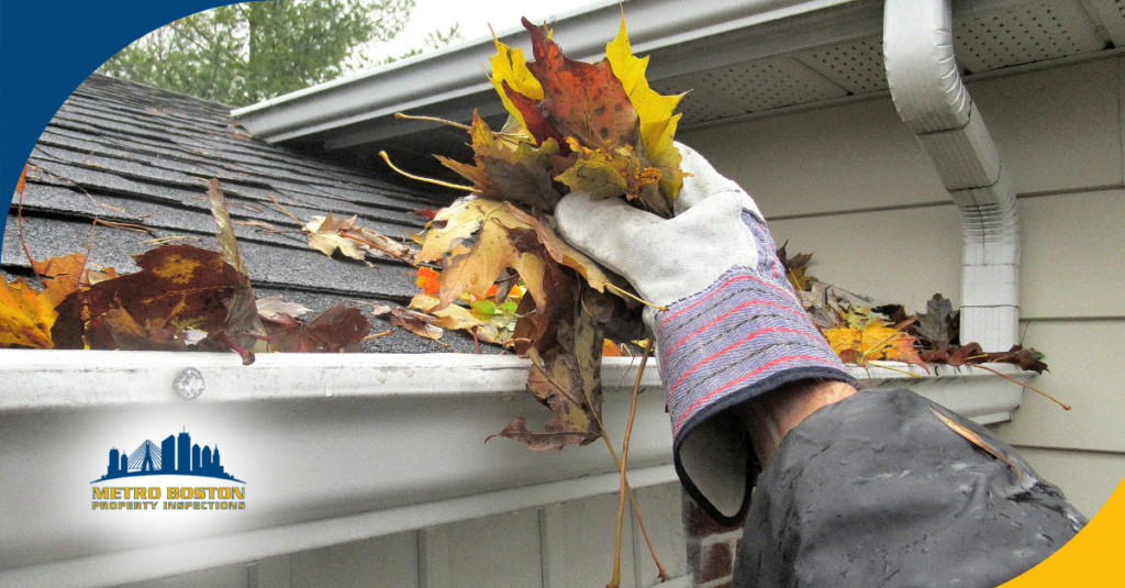 a person wearing a glove and cleaning out a gutter filled with fallen leaves