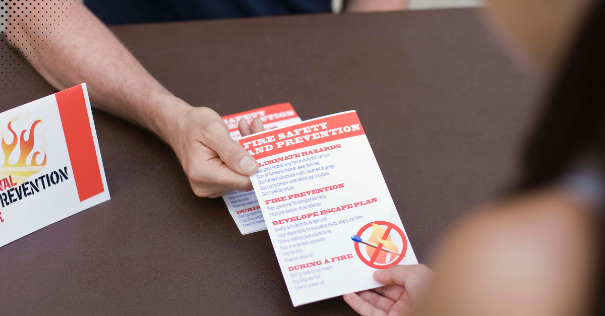 Person handing out a fire safety and prevention pamphlet 