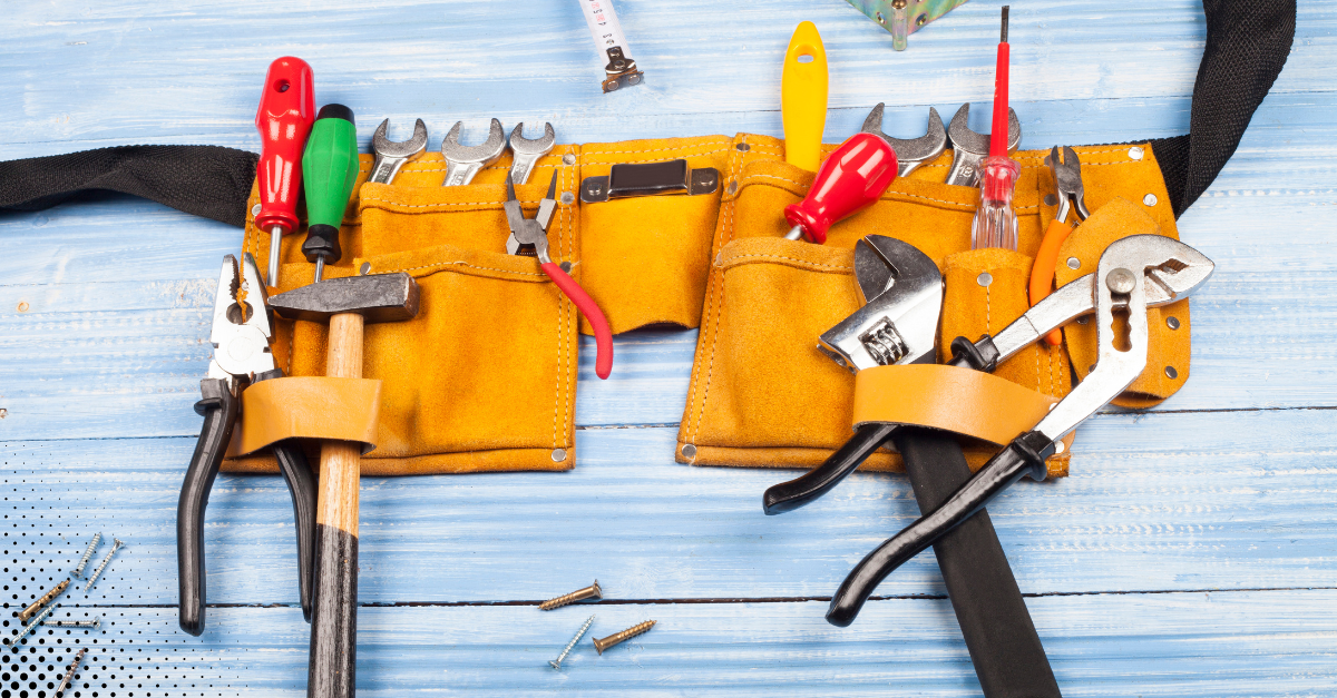 A full tool belt with various hand tools neatly arranged on a blue wooden surface.
