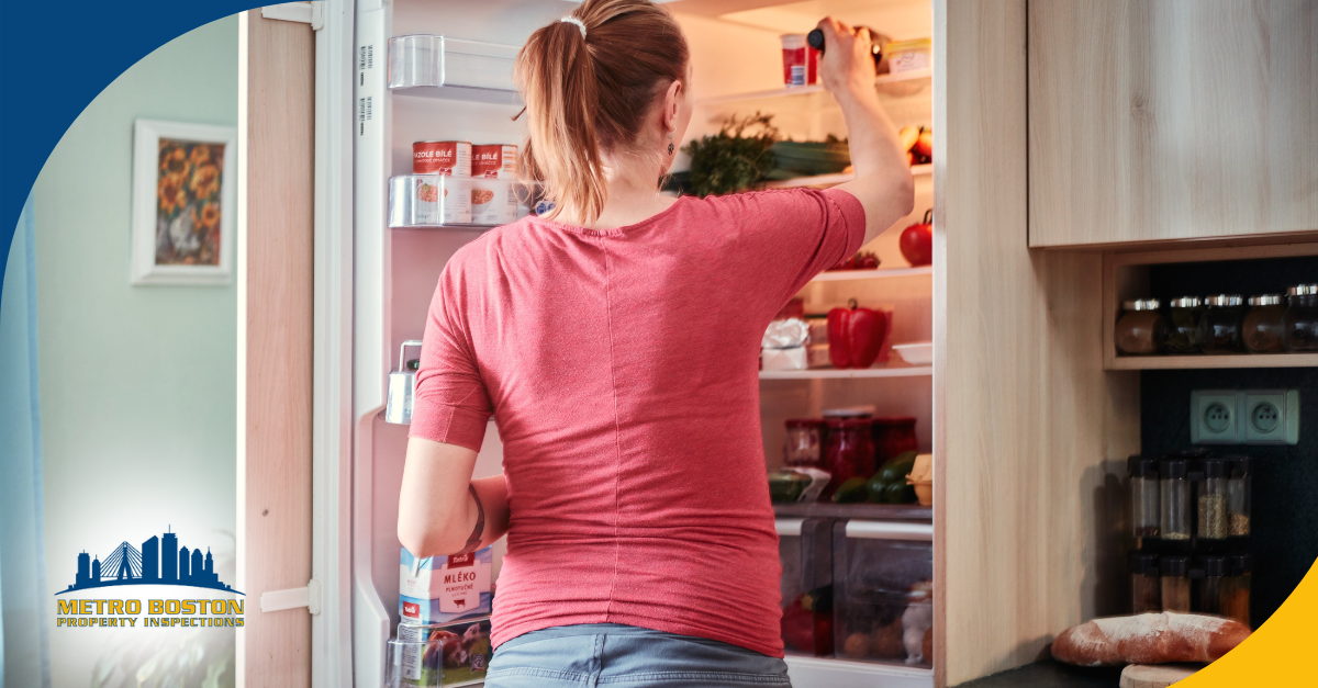 Woman reaching into a refrigerator filled with food and drinks.