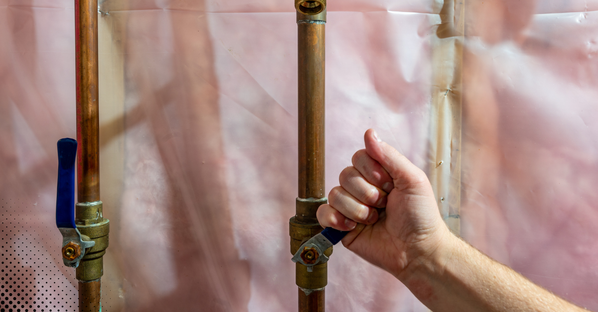 Hand turning off the main water shutoff valve.