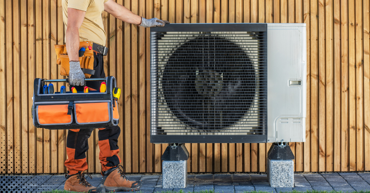 Technician inspecting and preparing an outdoor HVAC unit with tool bag for maintenance.