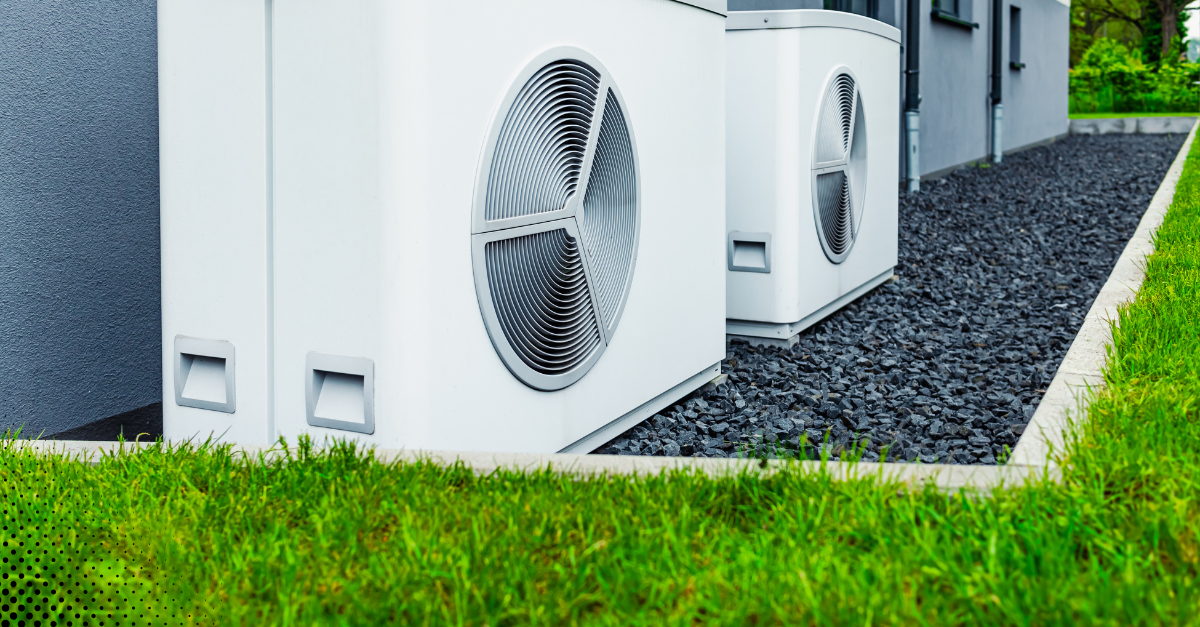 Exterior view of two outdoor HVAC units installed beside a modern home with landscaped yard.