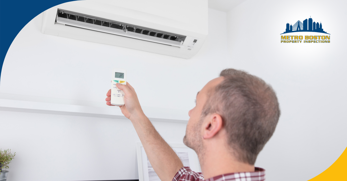 Homeowner using remote to adjust wall-mounted air conditioning unit during inspection in Metro Boston.